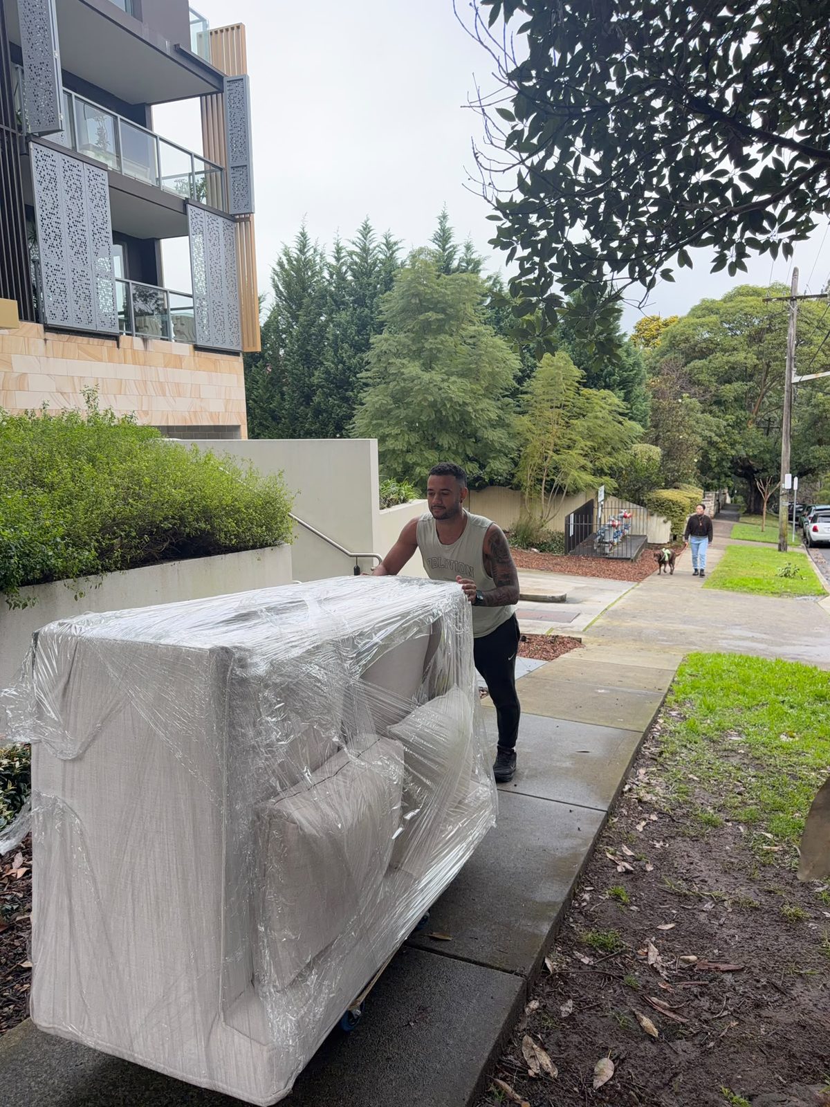 Mover pushing wrapped sofa on Sydney street
